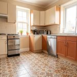 Cuisine lumineuse en location où un ancien carrelage est recouvert par un revêtement de sol amovible aux tons beige et terre cuite, sans modifier les éléments existants.