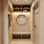 Entrée étroite sans fenêtre aménagée pour quatre personnes avec rangements intégrés, quatre patères, banc, miroir rond et éclairage chaleureux.